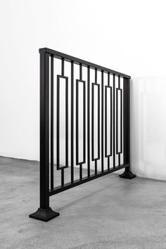 a black and white photo of an iron fence on concrete floor next to a wall