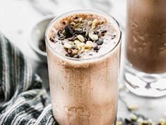 two glasses filled with chocolate milkshakes on top of a white and black towel