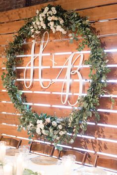 the table is set with candles, plates and flowers in front of a wooden sign that says h & b