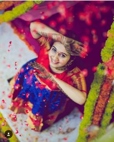 a woman is sitting under an umbrella covered in flowers and confetti as she poses for the camera