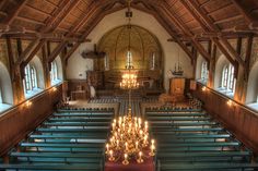 the interior of an old church with pews and chandeliers lit by candles