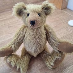 a brown teddy bear sitting on top of a wooden floor