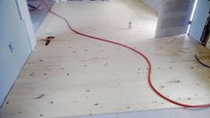 a room that is being remodeled with wood flooring and red hose connected to the wall