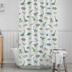 a shower curtain with dinosaurs on it and a stool in front of the bathtub