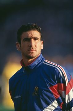 a soccer player in blue and white uniform looking at the camera with his head tilted