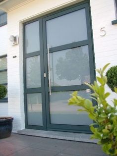 two potted plants are sitting in front of a building with glass doors and windows