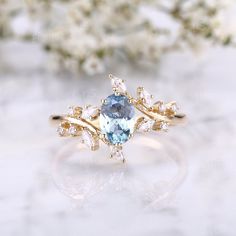 a ring with an aqua and white topazte stone surrounded by small diamond accents