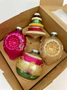 an open box with four ornaments in it