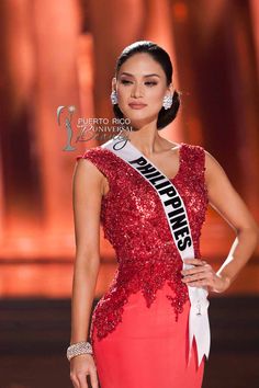 a woman in a red dress with a white sash on her head and an award around her neck