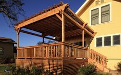 a wooden porch with a pergolated roof and stairs leading up to the house