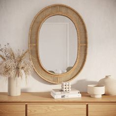 a wooden dresser topped with a mirror and vase