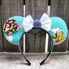 a mickey mouse ears headband with candy and candies on the top, sitting in front of a wooden fence