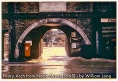 an old photo of a flooded street under a bridge