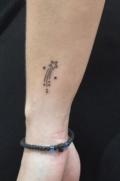 a woman's wrist with a star and arrow tattoo on the left side of her arm