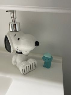 a snoopy dog soap dispenser sitting next to a little blue bear