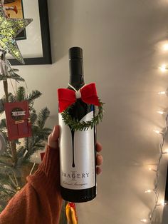 a person holding a wine bottle with a red bow on it