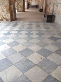 an empty room with stone walls and flooring that is grey and white checkered