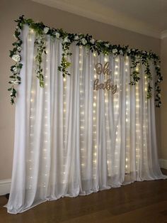 the curtain is decorated with white flowers and greenery, while lights shine on the wall behind it