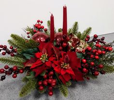 a christmas centerpiece with candles and poinsettis