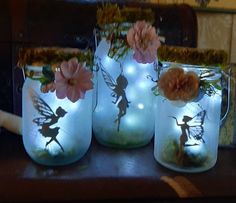 three mason jars with fairy lights and flowers in them