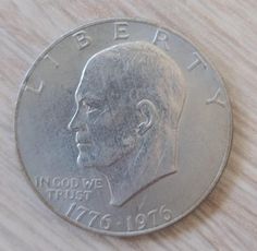 a close up of a coin on a wooden surface with the image of a man's face