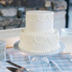 a three tiered white cake sitting on top of a table next to silverware