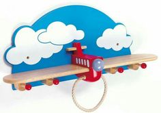 a wooden toy airplane hanging on a wall with clouds above it and a rope attached to the handle