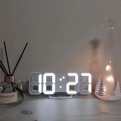 an alarm clock sitting on top of a table next to a glass bottle and candle