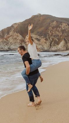 a man carrying a woman on his back at the beach