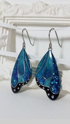 the earrings are blue and black with white dots on them, as well as an intricate design