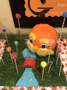 a pumpkin decorated like a scarecrow with lollipops in front of it