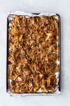 shredded meat in a baking pan on top of a white countertop, ready to be cooked