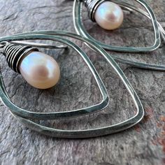 A pair of genuine freshwater pearls are carefully wrapped in sterling silver wire. The luminous pearls are very pale peach in color. The pair is framed by sterling silver petal shapes which I have formed, soldered, and textured by hand. The earrings hang from handformed Sterling Silver earwires. The silver has been oxidized and polished to create the patina finish. Be sure to see all photos and video for size and color reference. Total Earring Length: About 1 and 3/4" Handmade Silver Pearl Earrings In Pear Shape, Handmade Silver Pear-shaped Pearl Earrings, Silver Teardrop Wire Wrapped Pearl Earrings, Pale Peach, Color Reference, Patina Finish, Handmade Sterling Silver, Silver Wire, Sterling Silver Earrings