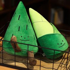 a green stuffed toy sitting on top of a wooden table next to a wire basket