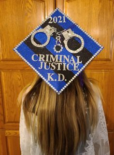 a woman wearing a blue graduation cap with handcuffs on it's head and the words,