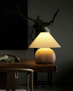 a table lamp sitting on top of a wooden table next to a vase filled with flowers