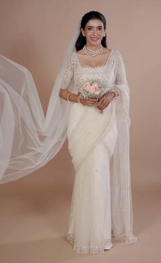 a woman in a white sari and veil posing for the camera with her hands on her hips