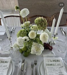 the table is set with white and green flowers, silverware, and menus