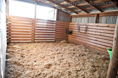 the inside of a barn with hay on the floor and wooden slats around it