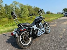 a black motorcycle parked on the side of a road next to a grassy field and trees