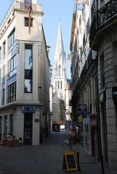 an empty city street with buildings on both sides and a clock tower in the background