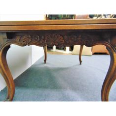 an old wooden table with ornate carvings on the top and bottom, sitting in a room