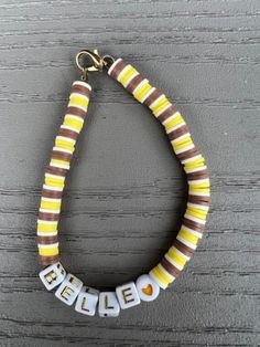 Clay beaded bracelet with Belle spelled with beads. Bracelet is yellow, white, and brown on elastic rubber string with a brass clasp. Brown Clay Bead Bracelet, Brown Bracelet, Yellow And Brown, Clay Beads, Arm Band, Wrap Bracelet, Jewelry Bracelets, Bracelet, Beaded Bracelets