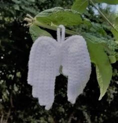 an angel ornament hanging from a tree with green leaves in the foreground