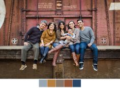 a group of people sitting on top of a wooden bench in front of a rusted building