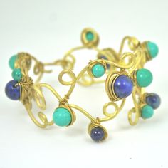 I make this gorgeous bangle with brass with lapis lazuris and howlite.It looks so stunning and great to wear to a party or to the beach. If you like to wear in set , I also have collar  and earring to match! Your bangle will  be packed in a hand woven box  or a gift pouch. Unique Handmade Blue Bangle, Blue Lapis Lazuli Jewelry For Festivals, Handmade Lapis Lazuli Jewelry For Festivals, Blue Brass Bracelet, Blue Wire Wrapped Bracelets, Unique Blue Wire Wrapped Bracelets, Unique Blue Wire-wrapped Bracelets, Bohemian Gold Cuff Bracelet With Natural Stones, Bohemian Gold Wire Wrapped Cuff Bracelet