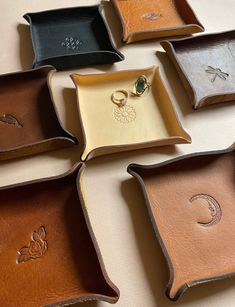 six trays with different designs on them sitting on a table together, one has a ring in the middle