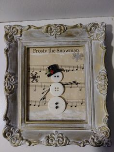 a snowman made out of buttons and sheet music in a frame on the wall