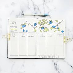 a planner with blue flowers on it next to a pen and paper clippings