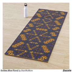 a yoga mat with an orange and blue design on it next to a white vase